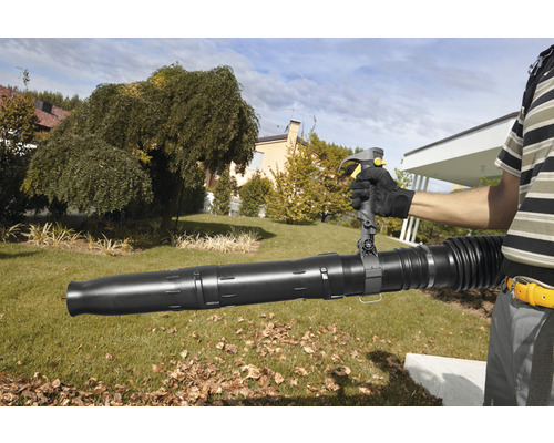 Eine Person bedient einen Laubbläser im Garten.