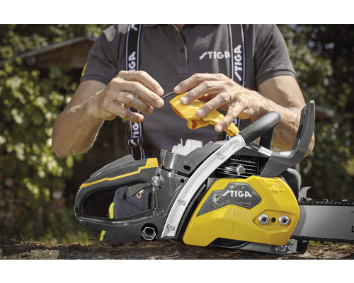Personne remplissant une tronçonneuse avec de l''huile. Logo Stiga.