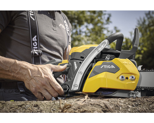 Une personne actionne une tronçonneuse STIGA jaune et grise.