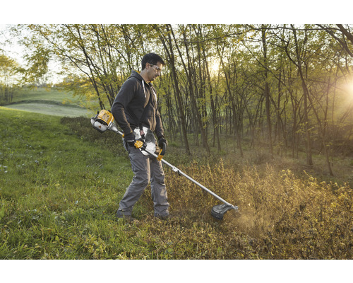Mann arbeitet mit einer Motorsense im Garten zur Landschaftspflege.