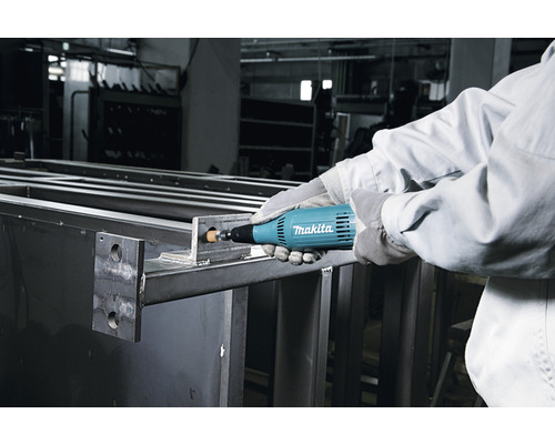 Une personne utilise une meuleuse droite Makita sur une pièce métallique.