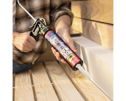 Anwender trägt Klebstoff mit einer Kartuschenpistole auf ein Holzbrett auf.