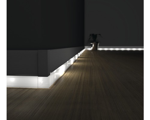 Szene mit indirekter Beleuchtung durch LED-Streifen entlang einer dunklen Wand und eines Holzbodens