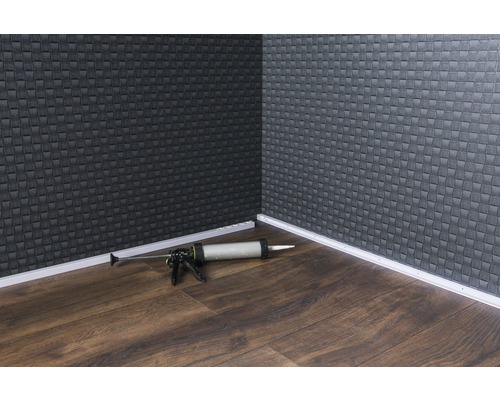 Eckbereich eines Raumes mit Fußleisten und einer Kartuschenpistole auf einem Holzboden