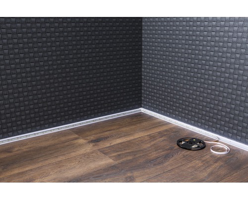 Ecke eines Raumes mit Wandpaneelen, LED-Leiste und Laminatfußboden