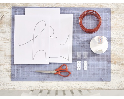 Materialien für ein DIY-Projekt auf einer Schneidematte, inklusive Draht, Schere und Papier