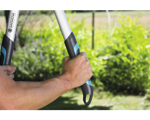 Une personne utilise une cisaille à branches Gardena dans le jardin.