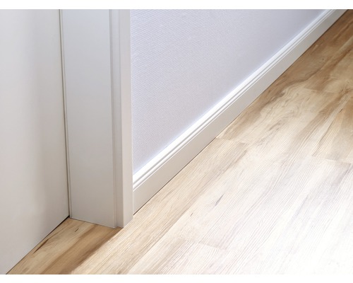 Detailansicht eines Raumes mit Laminatboden, einer weißen Fußleiste und einer Türzarge