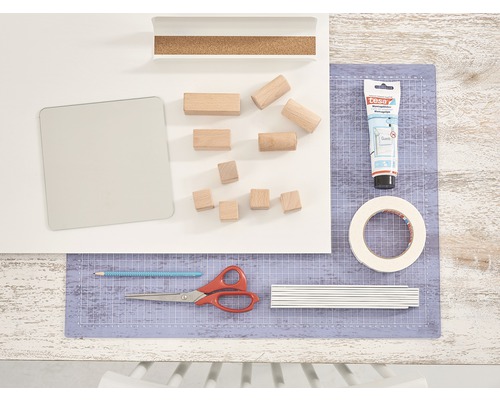 Bastelutensilien auf einer Arbeitsfläche mit Schneidematte, Klebstoff, Holzklötzen und Werkzeugen