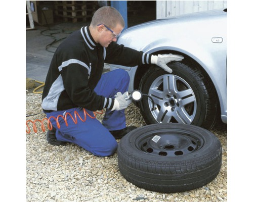 "Mann prüft Reifendruck mit Messgerät am Auto