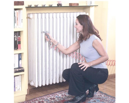 Frau reinigt Heizkörper mit Druckluftpistole