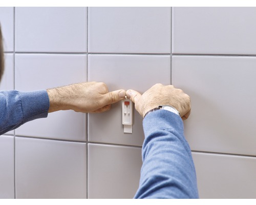 Un homme fixe un capteur d''humidité au mur