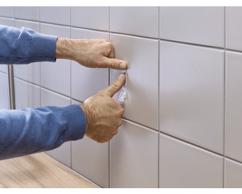 Application d''une bande adhésive sur un mur carrelé