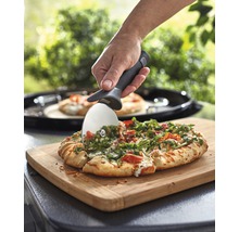 Une pizza est coupée avec un coupe-pizza sur une planche à découper.