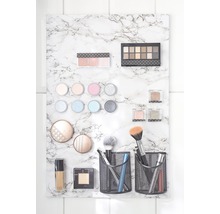 Produits cosmétiques fixés sur une plaque de marbre, incluant des palettes de fards à paupières, des pinceaux de maquillage et du fond de teint liquide
