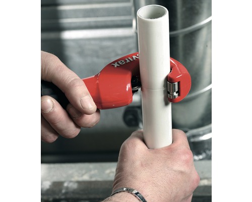 Une personne coupe un tuyau avec un coupe-tube.