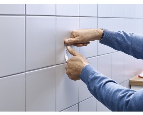 Application de bandes adhésives sur des carreaux par une personne