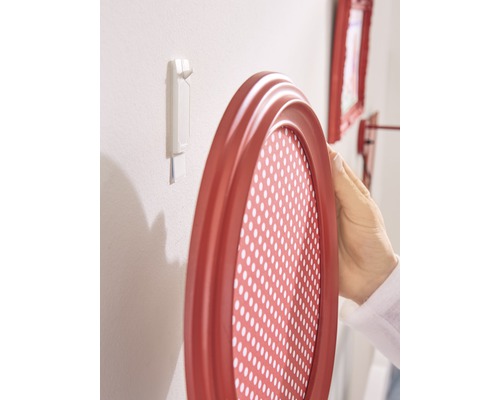 Ovaler Bilderrahmen wird mit einem Klebestreifen an einer Wand befestigt