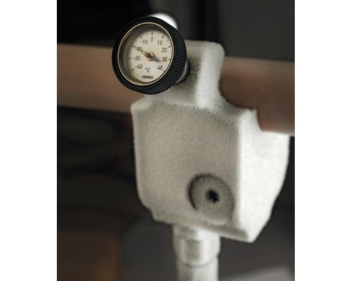 Gros plan d''un appareil de mesure de température gelé sur une canalisation