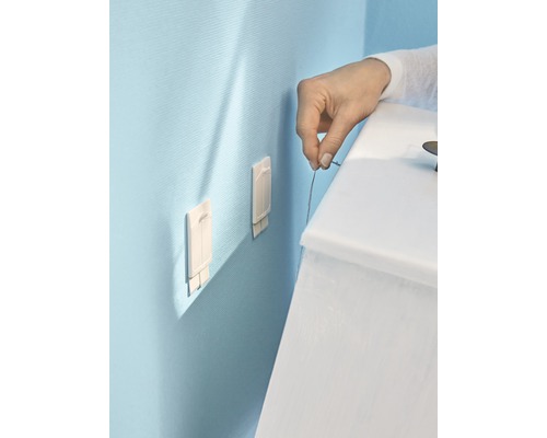 Montage von zwei Klebehaken an einer Wand mit einer Person, die ein Seil hält.