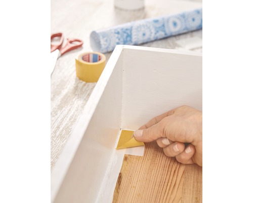 Anbringen von Malerkrepp an einem weißen Rahmen