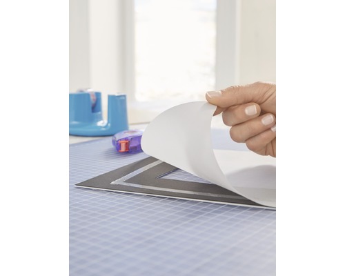 Hand, die Schutzfolie von einer Schneidunterlage abzieht