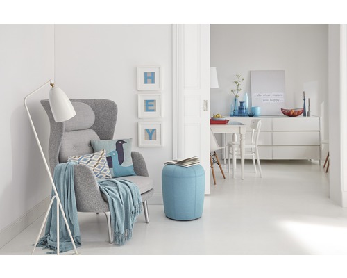 Wohnzimmer mit Sessel, Stehlampe und Pouf in heller, freundlicher Atmosphäre.