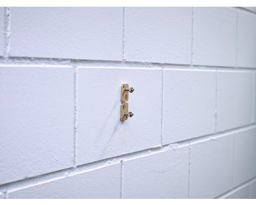 Deux supports dorés sont fixés à un mur blanc.