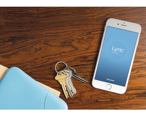 Smartphone mit Honeywell Lyric App, Schlüsselbund und Brieftasche auf einem Tisch