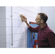 Un homme nettoie un mur avec une brosse à l''intérieur.
