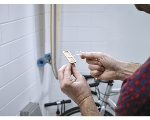 Un homme tient un support en bois pour équipements sportifs dans sa main