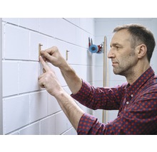 Un homme fixe un crochet en bois à un mur