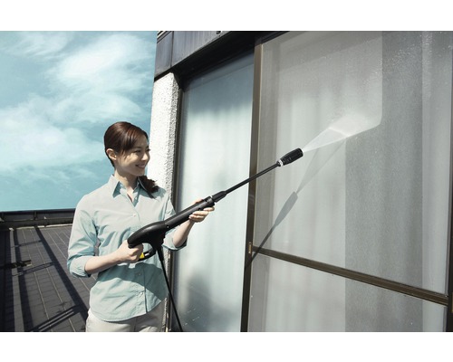 Frau reinigt Fenster mit einem Hochdruckreiniger