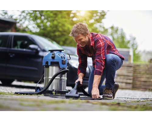 Mann benutzt einen Waschsauger zur Autoinnenreinigung im Freien.