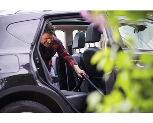 Mann saugt das Innere eines Autos mit einem Staubsauger