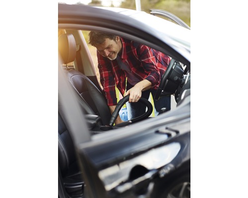 Mann reinigt Auto mit Staubsauger