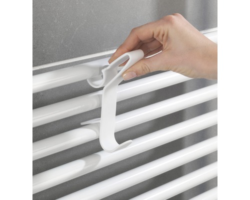 Une main accroche un crochet de radiateur à un radiateur
