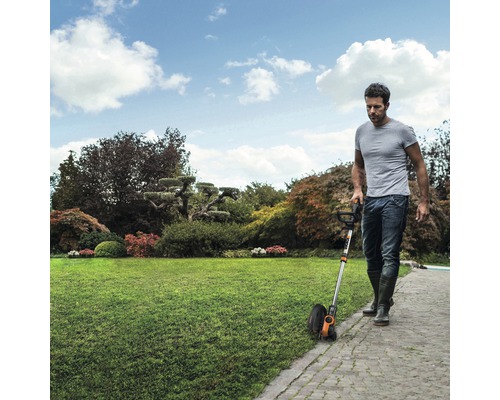 Ein Mann verwendet eine Rasenkantenschere im Garten, um die Rasenkante zu trimmen.