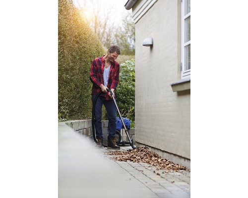 Mann saugt Laub mit einem Nass Trockensauger im Garten.