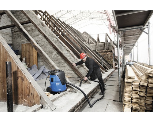 Handwerker benutzt einen Industriesauger zur Reinigung einer Baustelle.