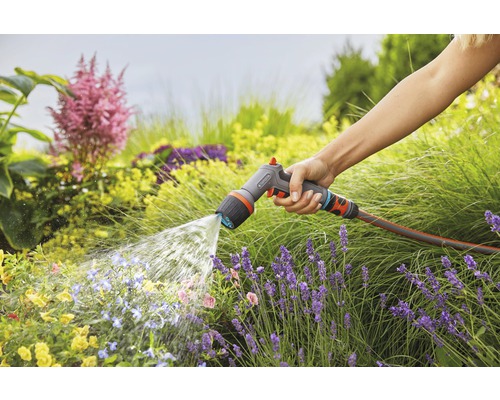 Eine Person bewässert einen Garten mit einer Gardena Gartenspritze.