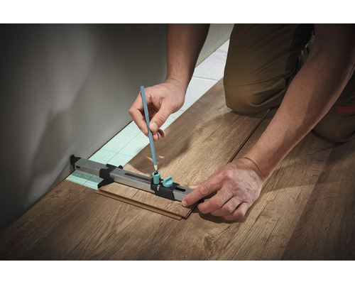 Person markiert Laminat mit Bleistift und Anreißwerkzeug für Laminat