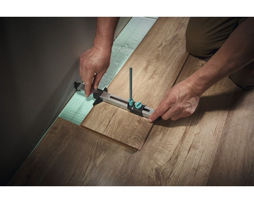 Zimmermann, der mit einem Anreißwerkzeug einen Laminatboden verlegt