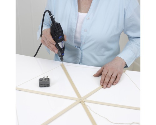 Eine Person bohrt mit einem Dremel Multifunktionswerkzeug ein Holzmodell.