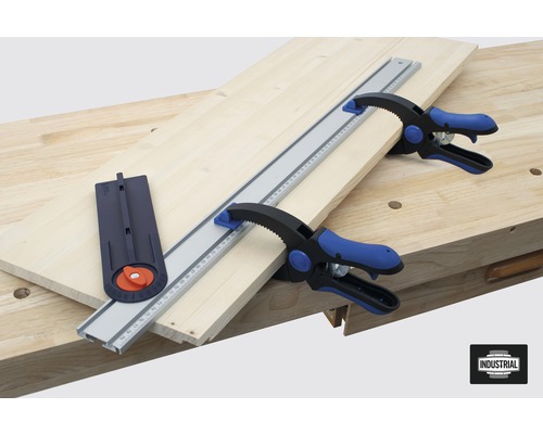 Pièce en bois fixée avec un rail de guidage, une butée angulaire et des serre-joints sur un établi.