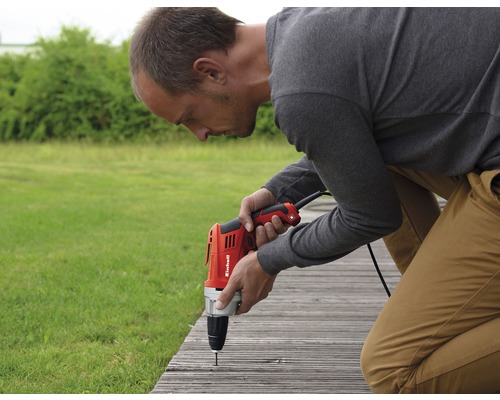 Un homme fixe une planche avec une perceuse