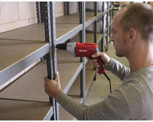 Une personne monte une étagère avec une visseuse-perceuse Einhell rouge.