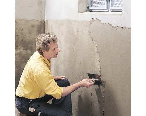 Une personne applique du plâtre sur un mur avec une truelle.