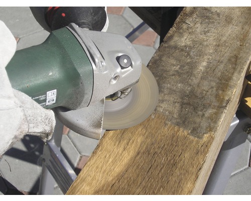 Eine Person glättet ein Stück Holz mit einem Winkelschleifer.