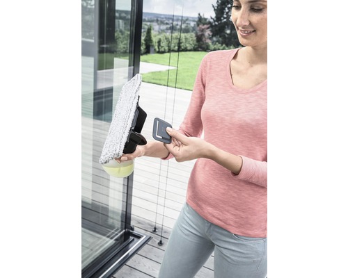 Une femme nettoie une vitre avec un nettoyeur de vitres.